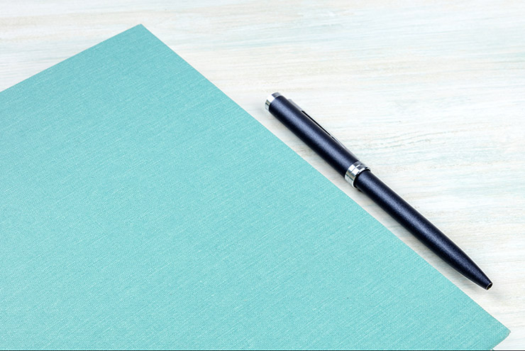 A photo of a teal blue journal with a pen, an elegant notebook or planner with copy space