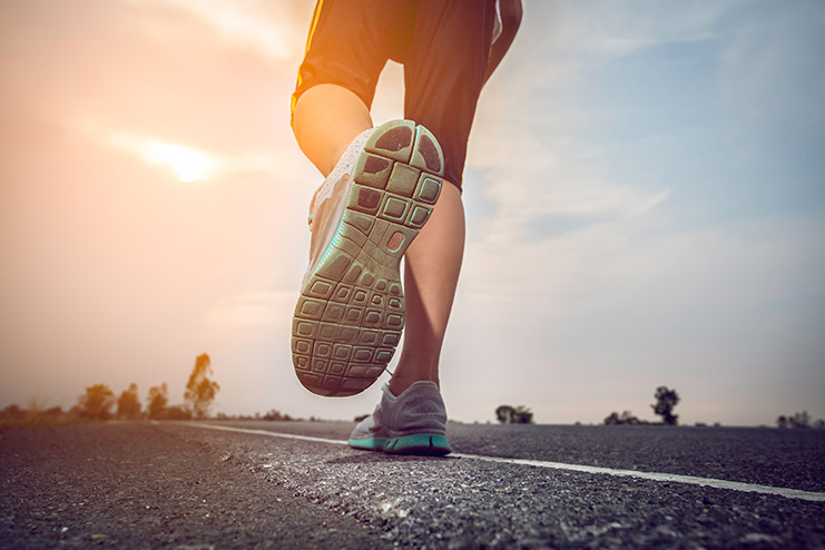 Man jogging on a road with the sun.