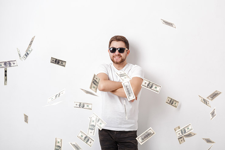 young happy man with a beard in white shirt standing under money